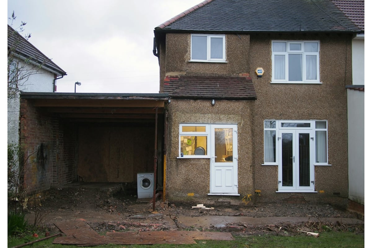 The back of a house mid-build, old lean-to stripped out and the ground dug up
