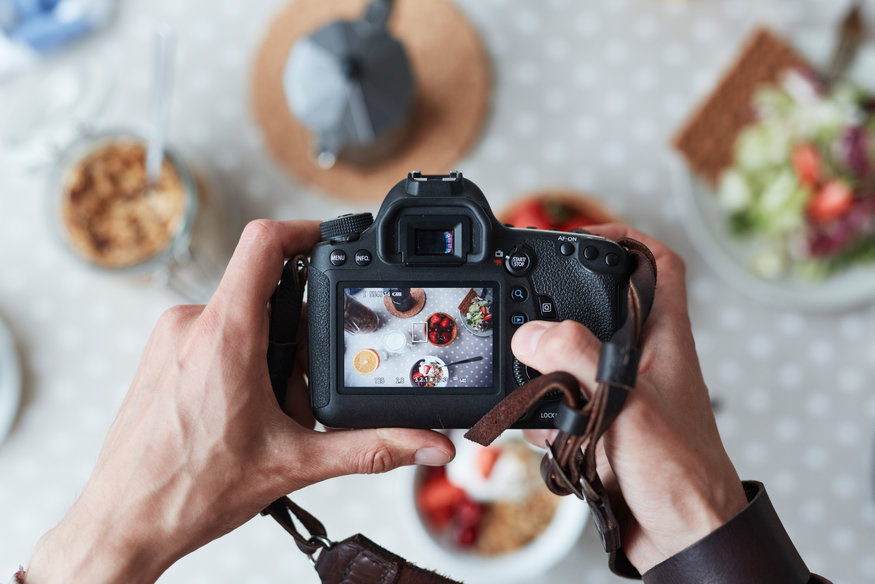 photographe tenant un appareil dans ses mains et photographiant de la nourriture