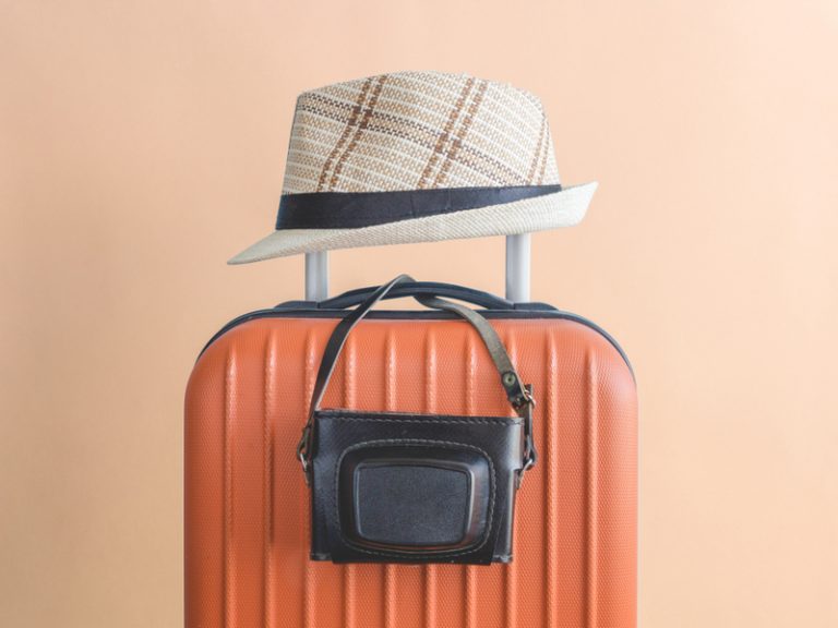 valise orange sur laquelle est posée un chapeau et un appareil photo