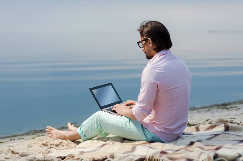Man working from a laptop on the beach
