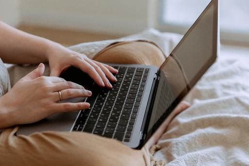 A woman sitting on bed using a laptop