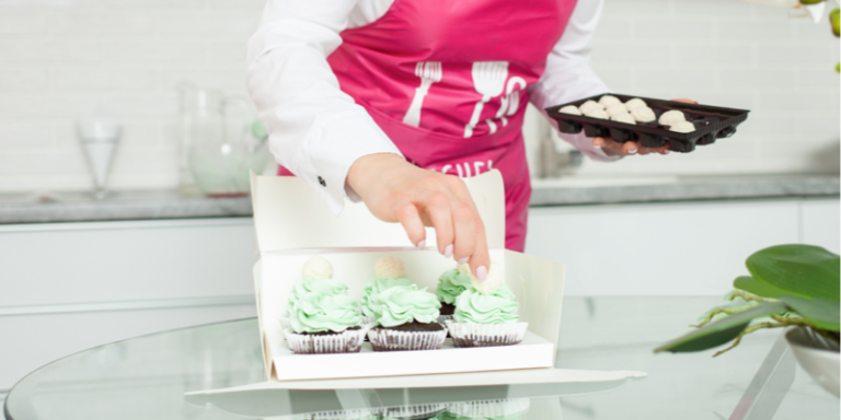 Woman placing cupcakes in a box on her kitchen
